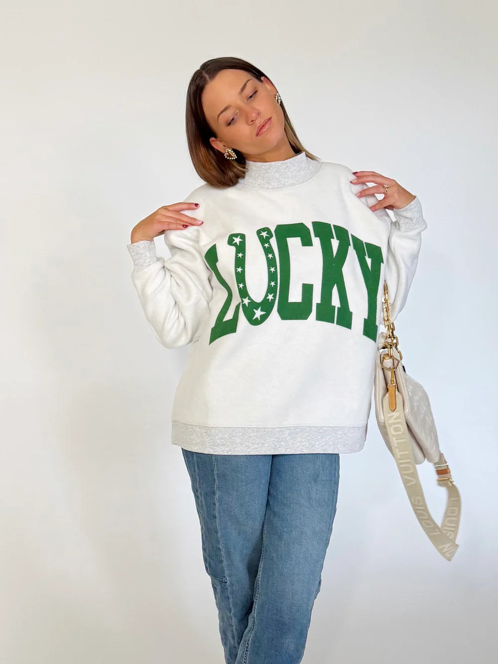 Person wearing a white sweatshirt with 'LUCKY' printed in green on a plain background