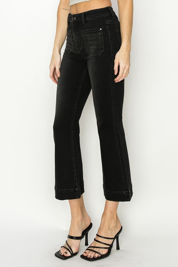 Person wearing black high-waisted jeans on a white background