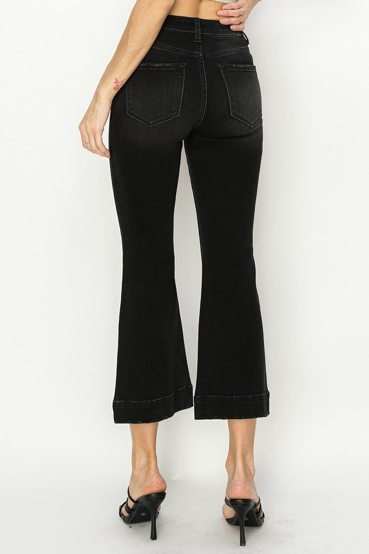 Black flared jeans worn by a person on a white background