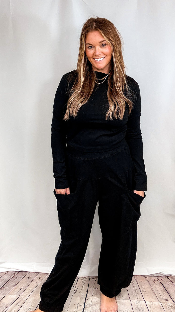 Woman wearing matching set with pocket pants and mock neck top on plain background