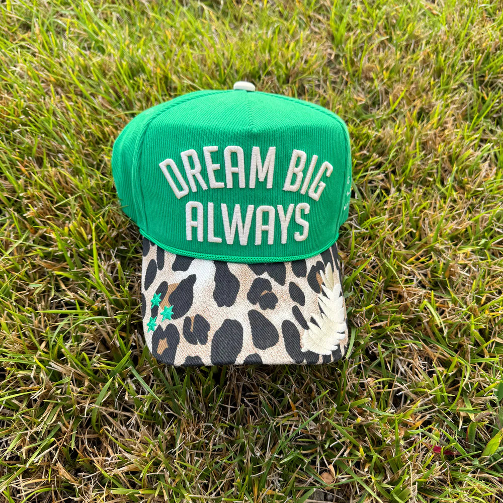 Green cap with 'Dream Big Always' text on grass