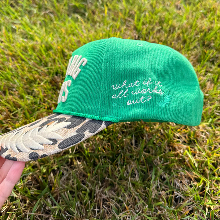 Green cap with leopard print bill held on grass