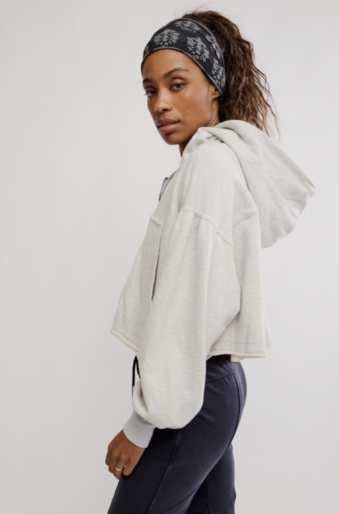 Woman wearing a light gray hoodie and dark pants on a white background