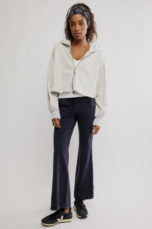 Woman wearing a light-colored jacket, dark jeans, and black sneakers on a white background