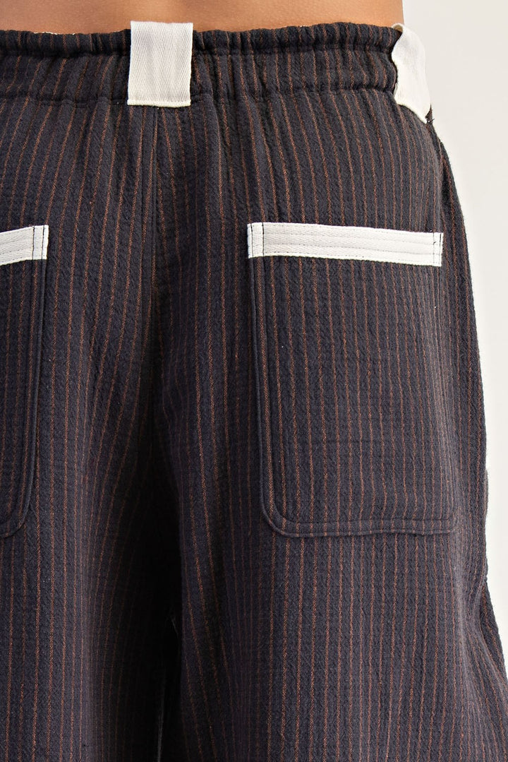 Close-up of the back of dark navy pinstriped trousers with white contrast stitching and white fabric tabs at the waistband.