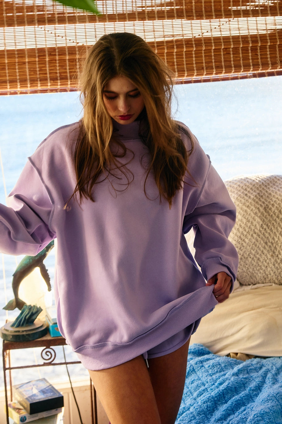 Woman wearing purple sweatshirt in bedroom
