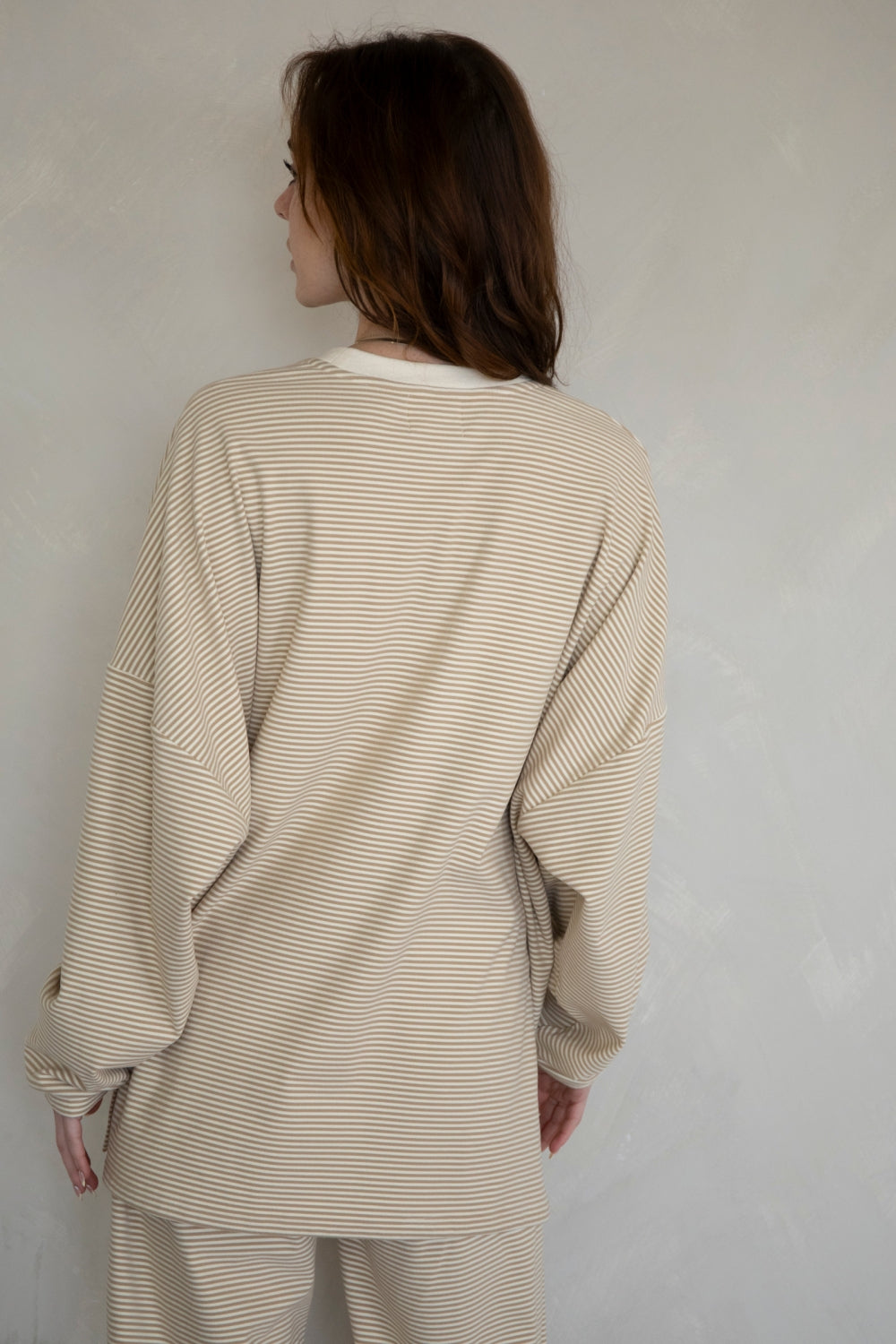 Person wearing a beige striped outfit against a plain background
