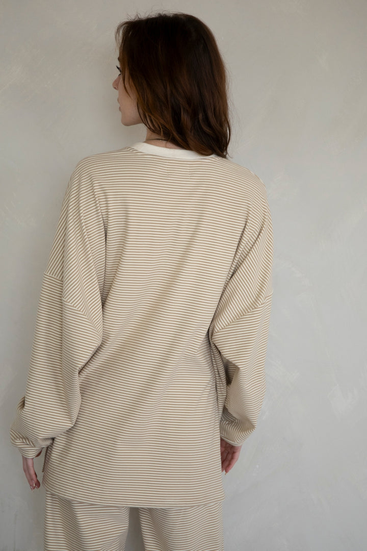 Person wearing a beige striped outfit against a plain background