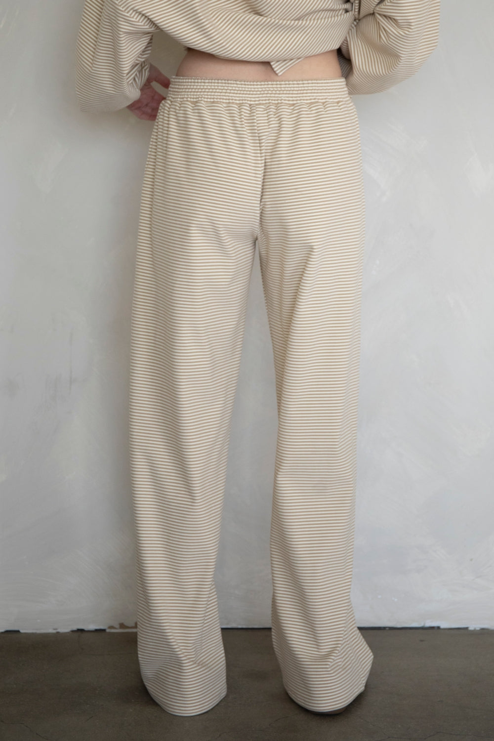 Person wearing beige striped pants against a plain background