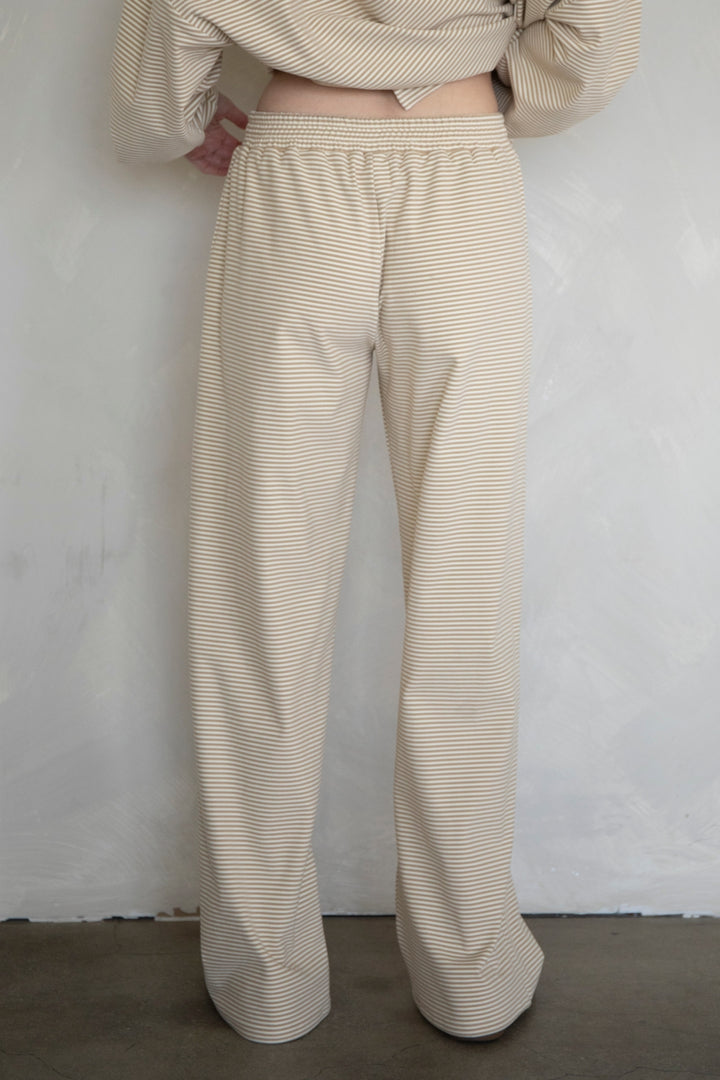 Person wearing beige striped pants against a plain background