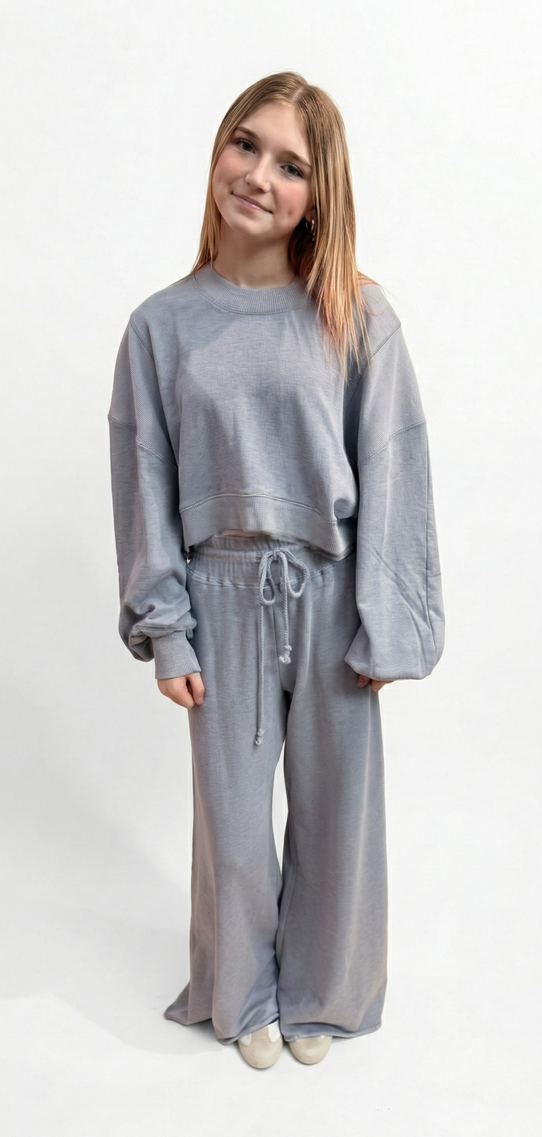 Person wearing a gray tracksuit on a white background