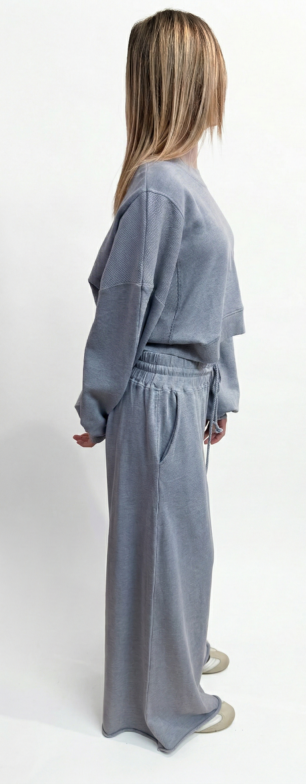 Woman wearing a gray robe standing against a white background