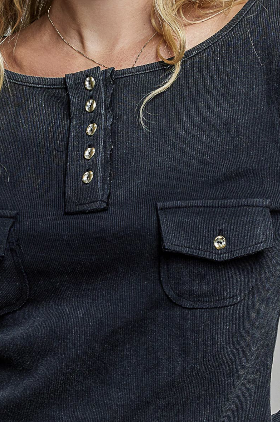 Close-up of a dark navy ribbed corduroy top with a buttoned henley neckline and a chest pocket, worn by a model.
