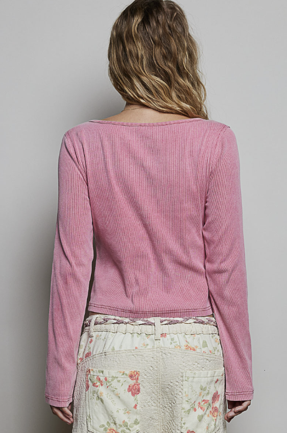 A woman shown from the back wearing a pink ribbed long-sleeve cropped top and a cream floral skirt against a plain light gray background.