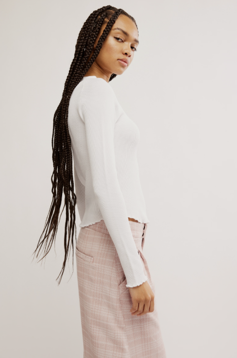 Woman wearing a white sweater and pink plaid pants on a plain background