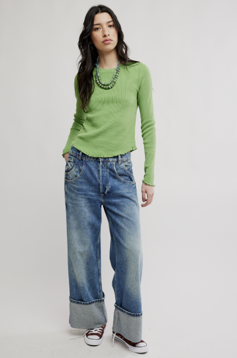 Woman wearing a green sweater and blue jeans on a white background