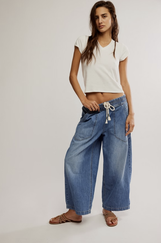 Woman wearing jeans and white tee on plain background