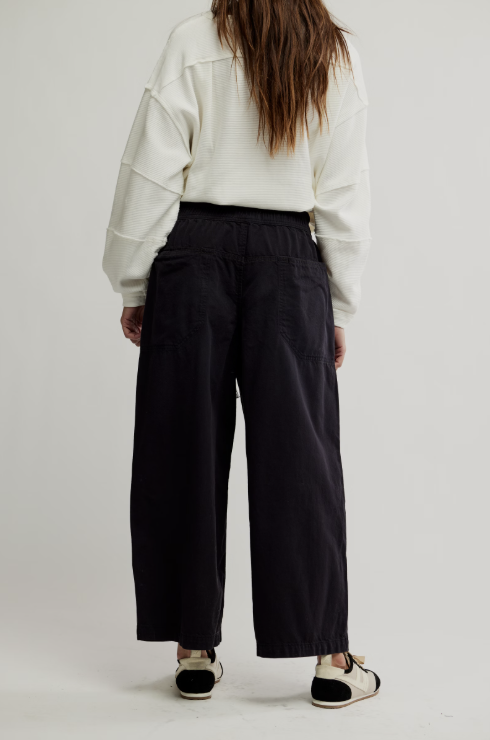 Person wearing a white jacket and black pants on a plain background