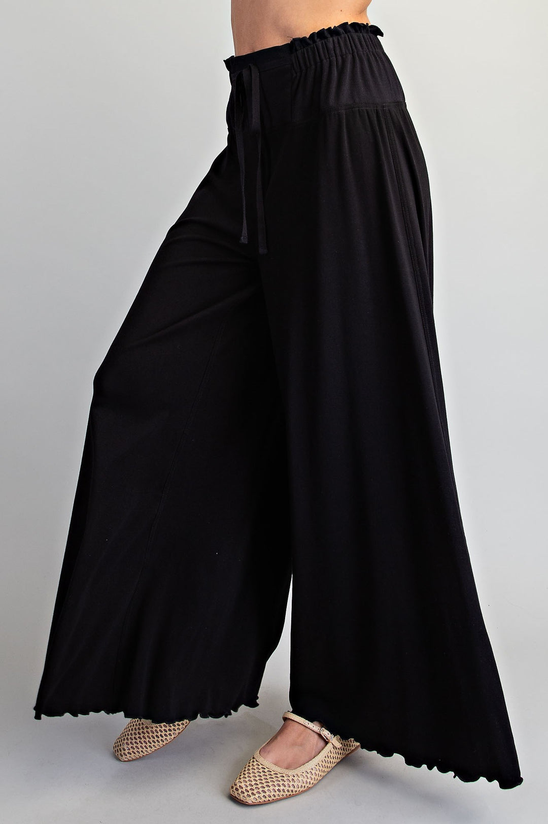 Black wide-leg cropped pants with a drawstring waistband, shown on a model wearing beige woven flat shoes against a light gray background.