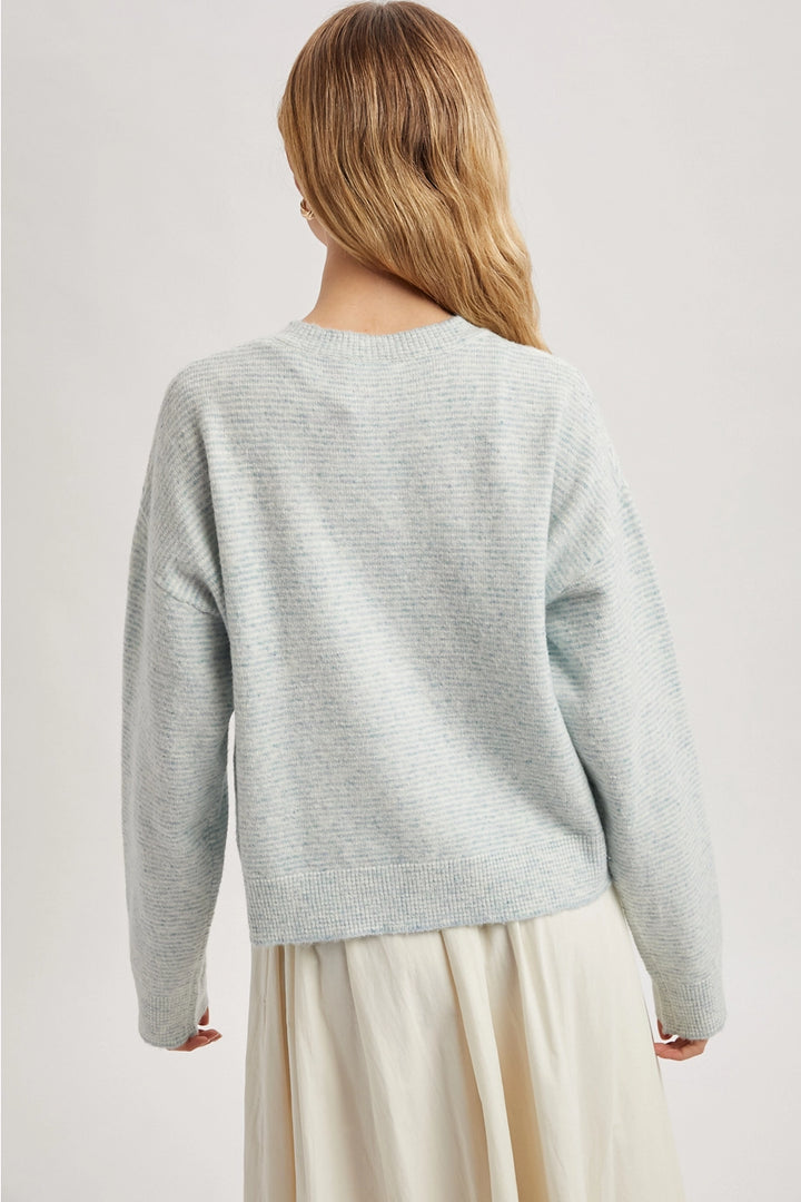 Person wearing a mint sweater with a plain background