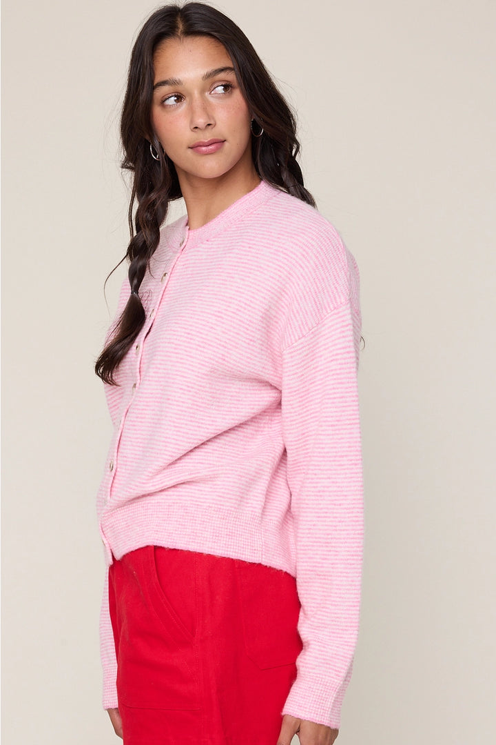 Woman wearing a pink sweater and red pants against a beige background
