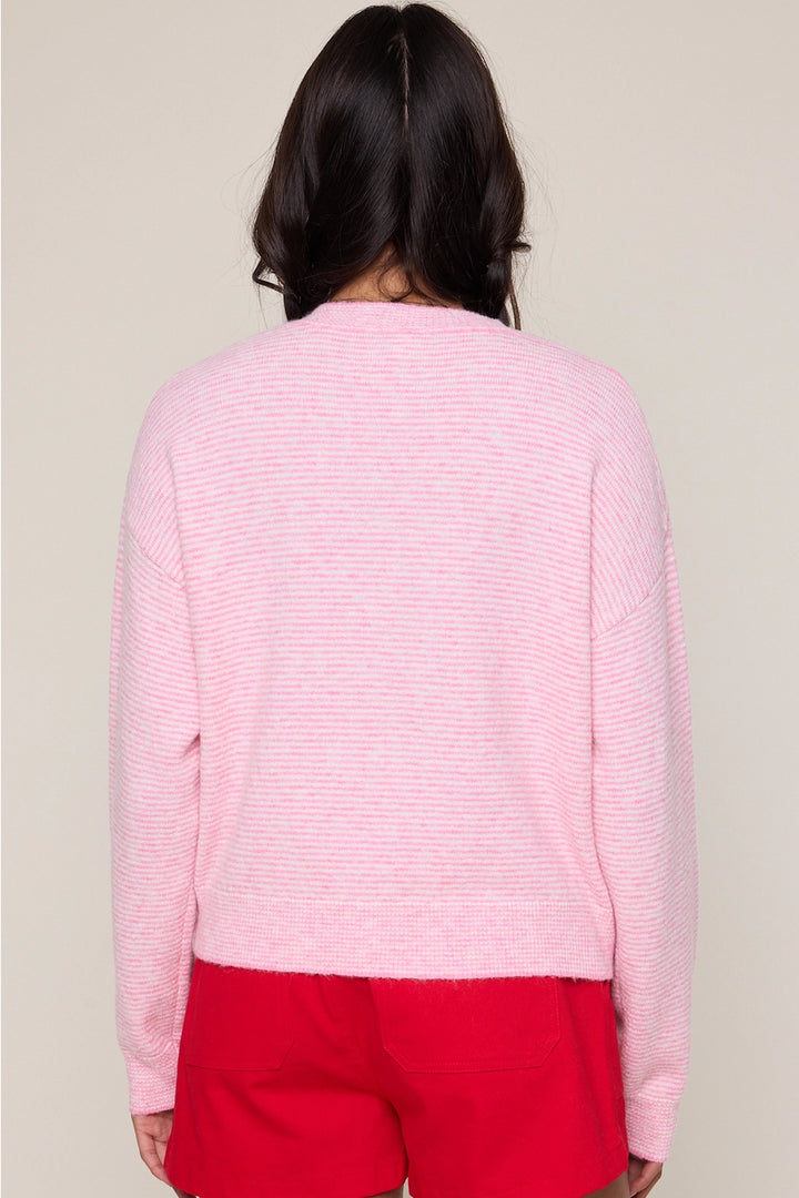 Person wearing a pink textured sweater and red pants on a plain background