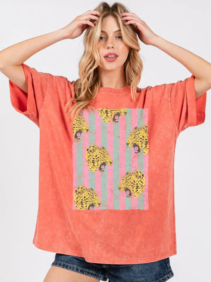 Woman wearing graphic tee with leopards and denim shorts on plain background