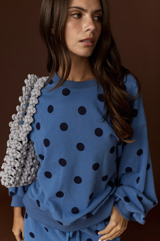 Woman wearing blue and black polka dot set on plain background