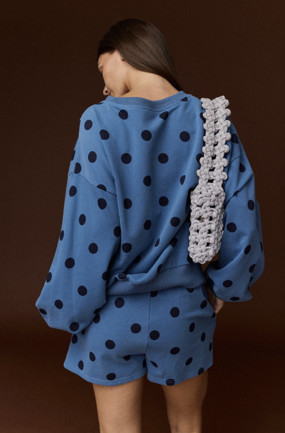 Woman shown from behind wearing blue and black polka dot set on plain background