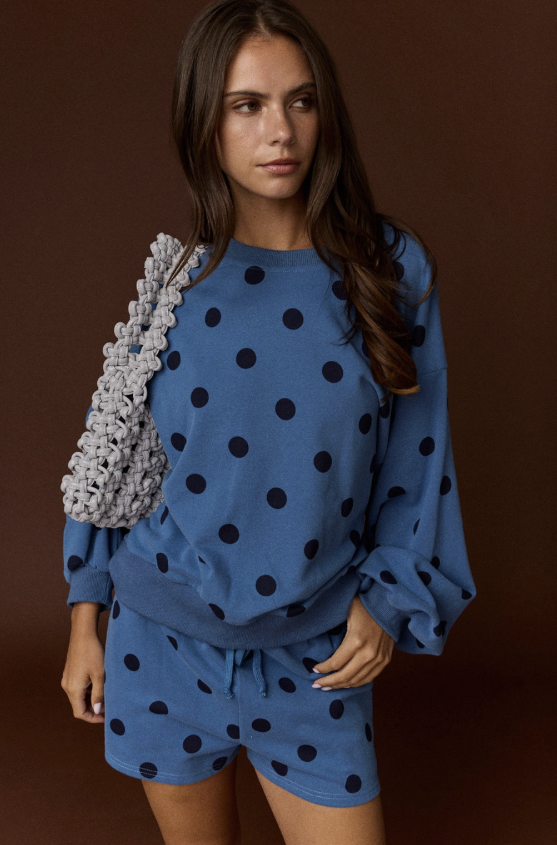 Woman wearing blue and black polka dot set on plain background
