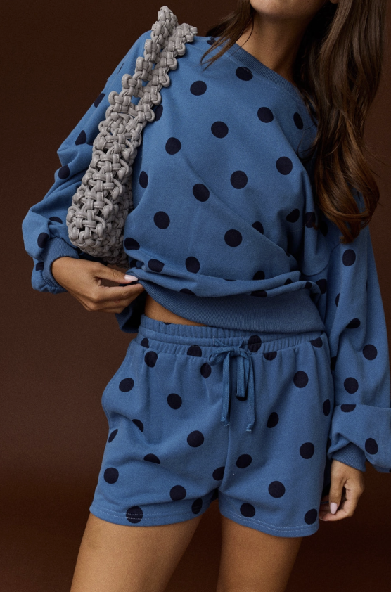 Woman wearing blue and black polka dot set on plain background