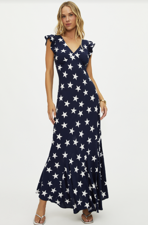 Woman wearing a navy dress with white star pattern on a white background