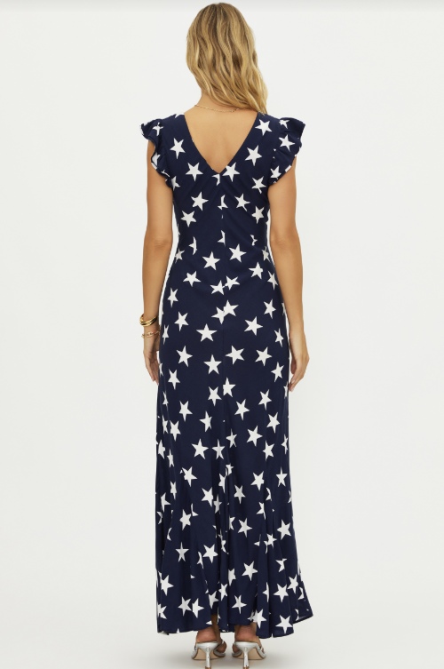 Back of woman wearing navy maxi dress with white star pattern on white background