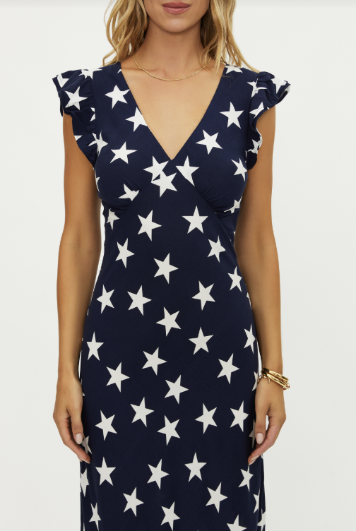 Woman wearing navy maxi dress with white star pattern on white background
