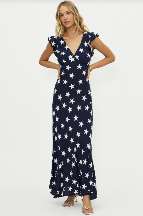 Woman wearing navy maxi dress with white star pattern on white background