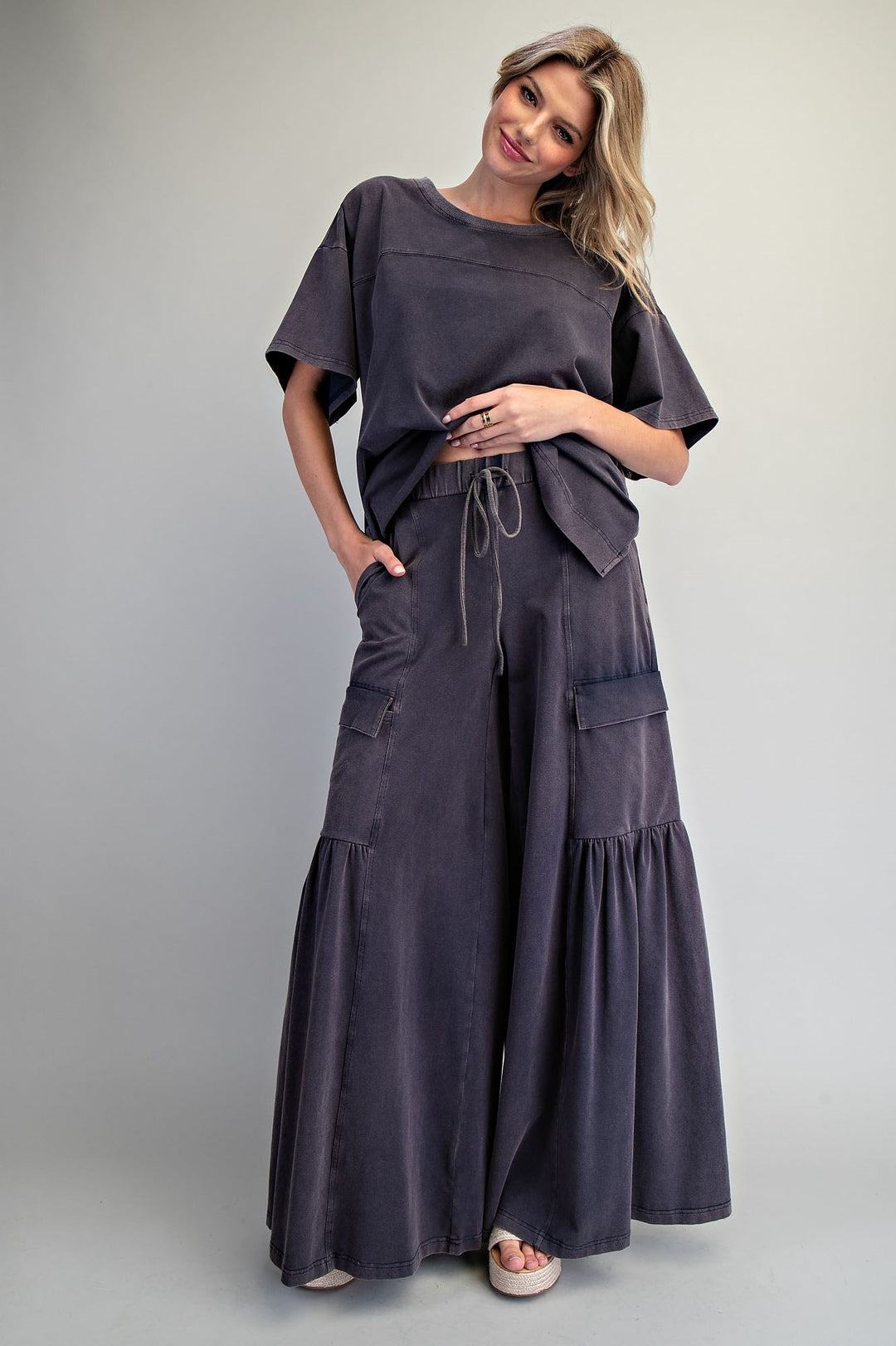 Woman wearing black wide leg pants and black shirt on plain background