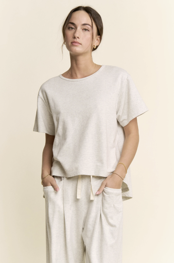 Woman wearing a plain white t-shirt and pants against a beige background