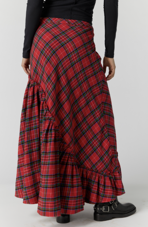 A red tartan plaid maxi skirt with tiered ruffle details, shown on a model from the back wearing a black long-sleeve top and black boots against a light gray background.