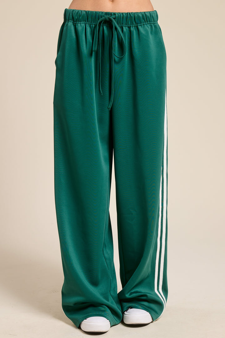 Person wearing green track pants on plain background