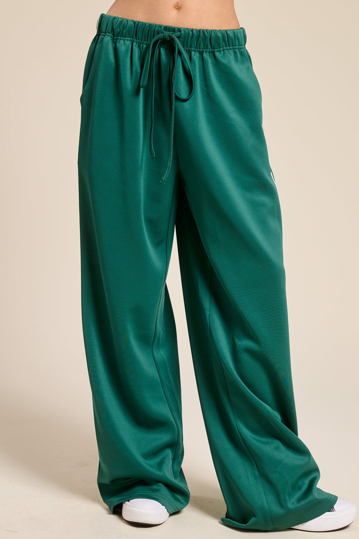 Person wearing green track pants on plain background