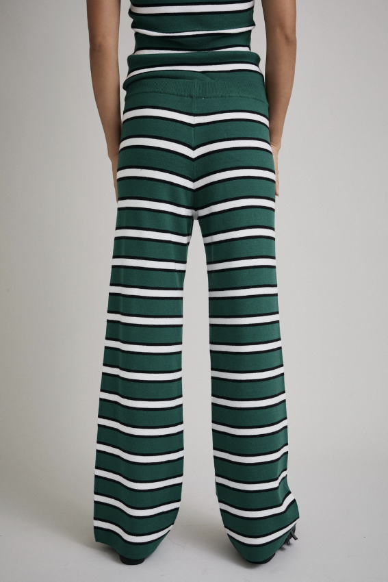 Woman wearing matching green, white and black set on plain background