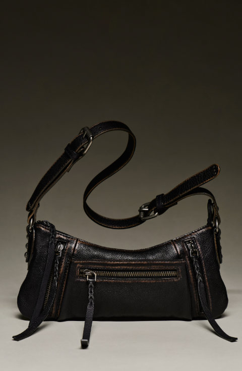 Black small purse with crossbody strap on beige background