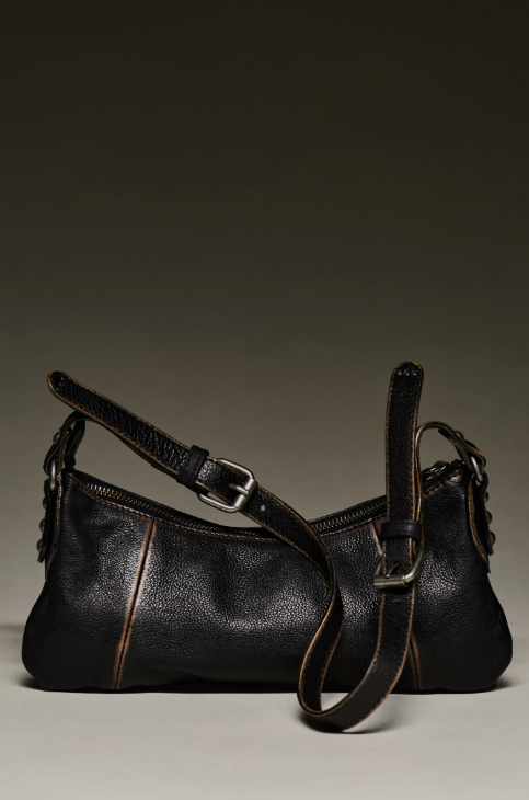 Black small purse with crossbody strap on beige background
