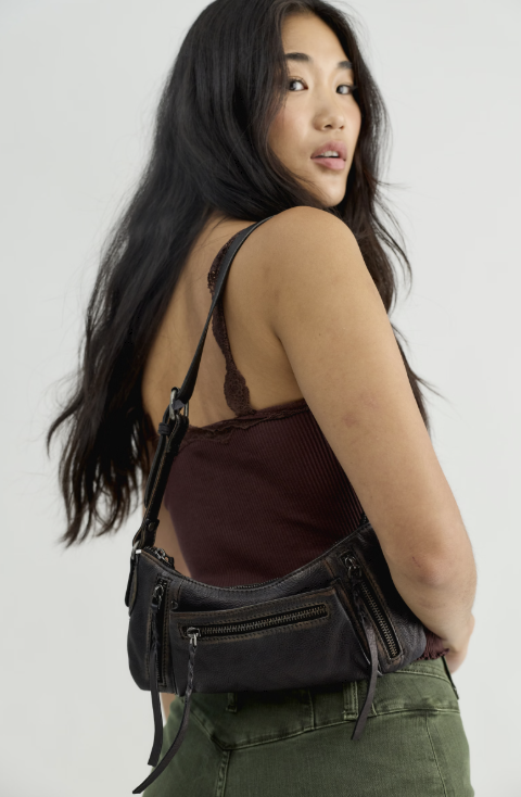 Woman wearing small black purse on her shoulder on white background