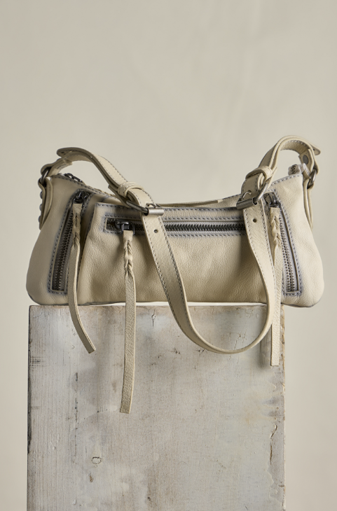 Small beige purse sitting on concrete block on beige background