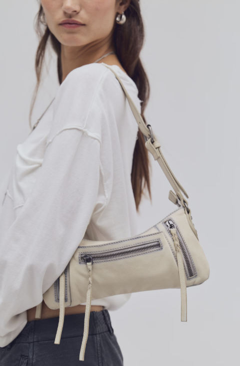 Woman wearing small beige purse on white background