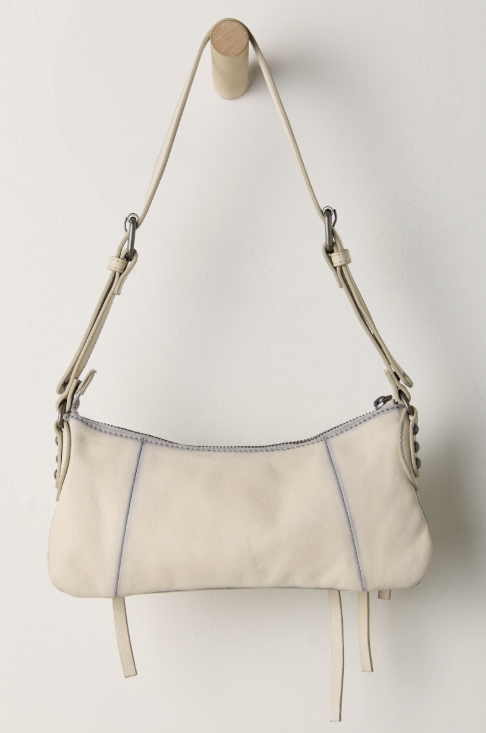 Small beige purse hanging on hook on white background