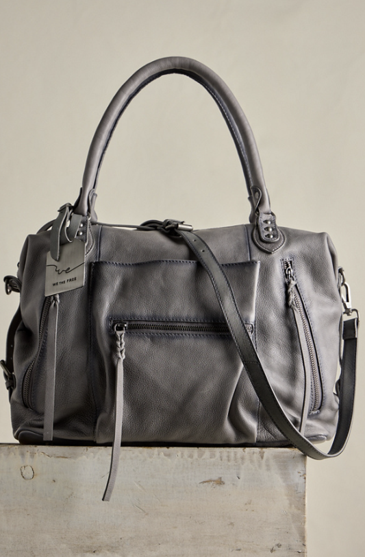 Large grey purse sitting on concrete block with beige background