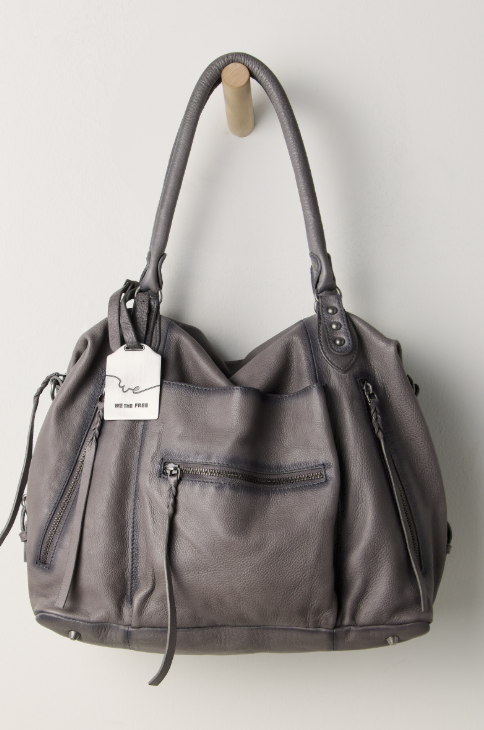 Large grey purse hanging on hook on beige background