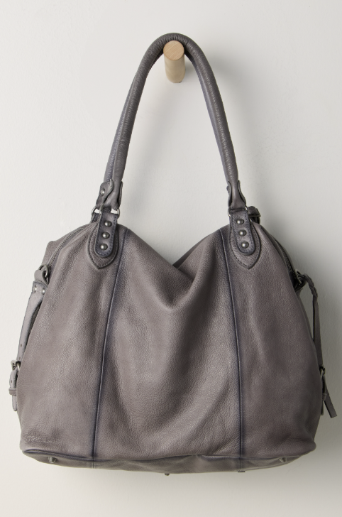 Large grey purse hanging on hook on beige background